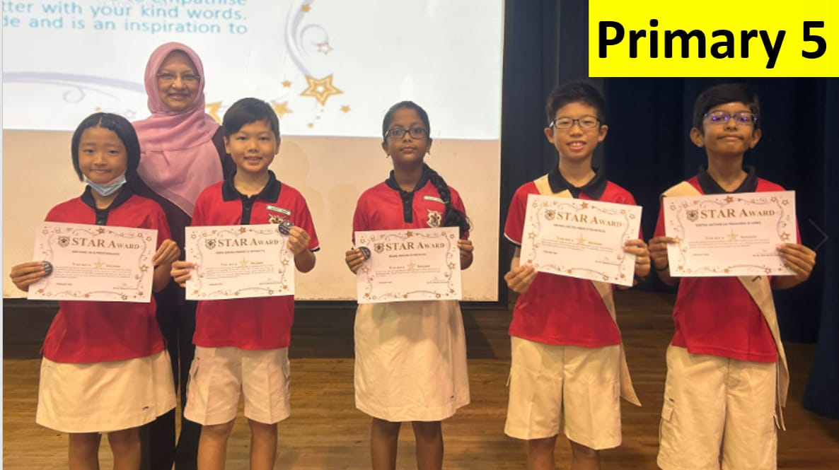 Five Primary 5 students in red uniforms hold Star Award certificates, standing with a teacher in a pink hijab.